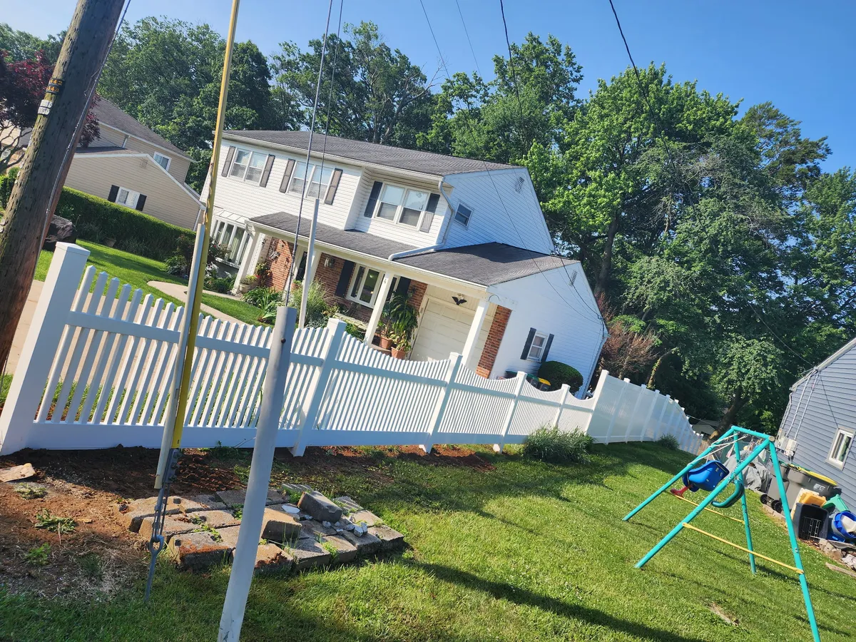 White vinyl picket fence installation around residential property with yard