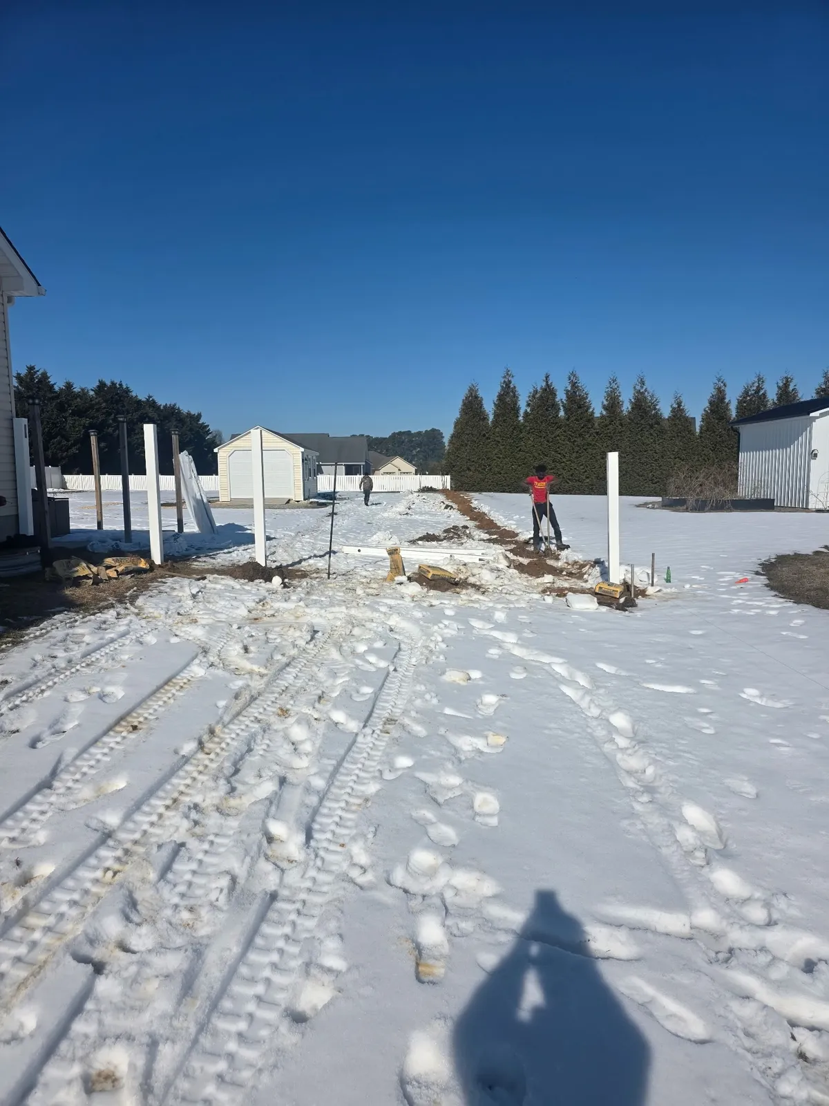 Vinyl fence posts being set in snowy winter conditions